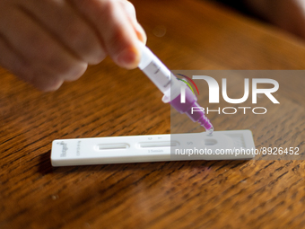 A woman drops a swab sample into an antigen test strip at home in L’Aquila, Italy, on September 29, 2022.  (
