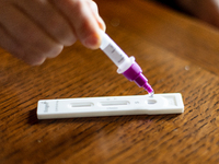 A woman drops a swab sample into an antigen test strip at home in L’Aquila, Italy, on September 29, 2022.  (