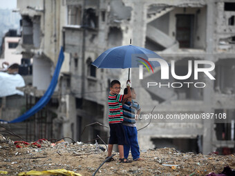 Palestinian Children holds an umbrella near a house that witnesses said was destroyed by Israeli shelling during the 50-day war in the summe...
