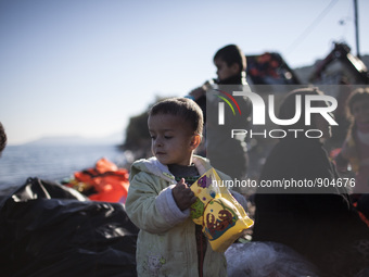 A child stands as refugees and migrants riding a dinghy reach the shores of the Greek island of Lesbos after crossing the Aegean Sea from Tu...