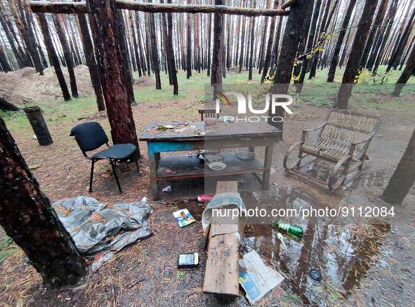 KHARKIV REGION, UKRAINE - OCTOBER 26, 2022 - Three chairs stay at the table in a camp in a forest near Izium after the liberation of the are...