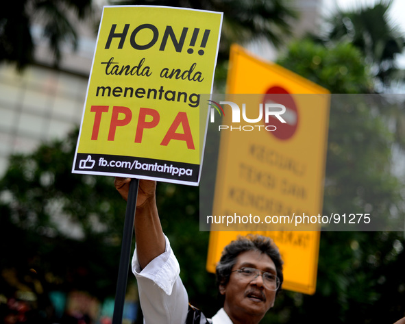 An activist holds up play cards during a protest rally against Trans-Pacific Partnership Agreement (TPPA) ahead of U.S. President Barack Oba...