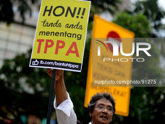 An activist holds up play cards during a protest rally against Trans-Pacific Partnership Agreement (TPPA) ahead of U.S. President Barack Oba...