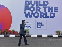 A man talks on his phone walks past a billboard of Global Investors Meet 2022 in Bangalore, 03 November, 2022.  (