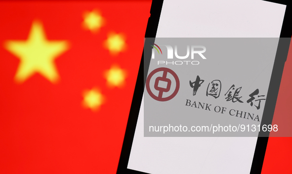 Bank Of China logo displayed on a phone screen and Chinese flag displayed on a screen in the background are seen in this illustration photo...