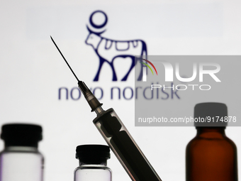 Medical bottles and syringe are seen with Novo Nordisk logo displayed on a screen in the background in this illustration photo taken in Krak...