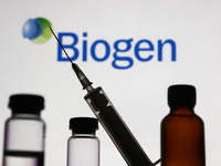 Medical bottles and syringe are seen with Biogen logo displayed on a screen in the background in this illustration photo taken in Krakow, Po...