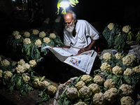 A cauliflower seller reads a newspaper at his shop in a marketplace in Kolkata, on November 12, 2022. India's retail inflation, measured by...
