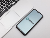 In this photo illustration a Merck logo seen displayed on a smartphone screen on a desk next to a Macbook in Athens, Greece on November 16,...
