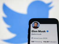 Elon Musk Twitter account displayed on a phone screen and Twitter logo displayed on a screen in the background are seen in this illustration...