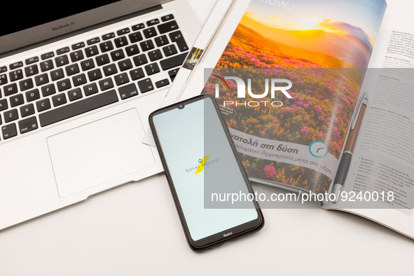 In this photo illustration a Royal Brunei airlines logo seen displayed on a smartphone screen on a desk next to a Macbook and atravel magazi...