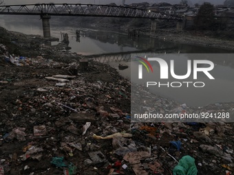 People walk over a bridge as garbage filled banks of River Jehlum is seen in Baramulla Jammu and Kashmir India on 24 November 2022 (