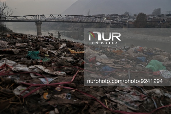 People walk over a bridge as garbage filled banks of River Jehlum is seen in Baramulla Jammu and Kashmir India on 24 November 2022 