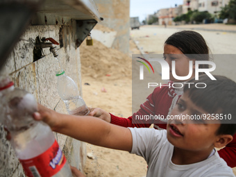 A Palestinian girl fills a bottle from a tap delivering drinking water for free in the Khan Yunis refugee camp in the southern Gaza Strip, o...