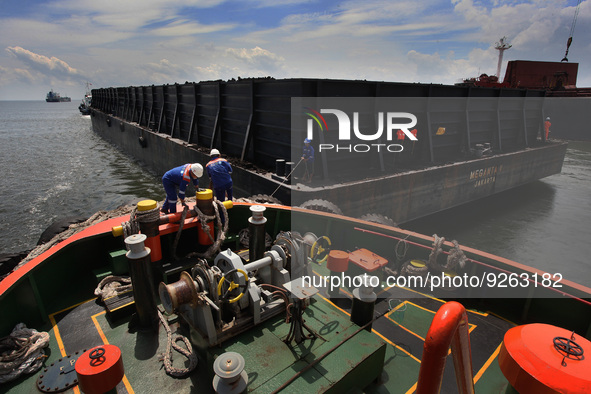 Officers tether a rope from the tugboat to the barge to carry out ship to ship services with the mother vessel in the Bangka Strait, Indones...