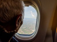 An elderly man is watching from the airplane window during the landing in a Ryanair Boeing 737 directed to Treviso A. Canova airport, on Nov...