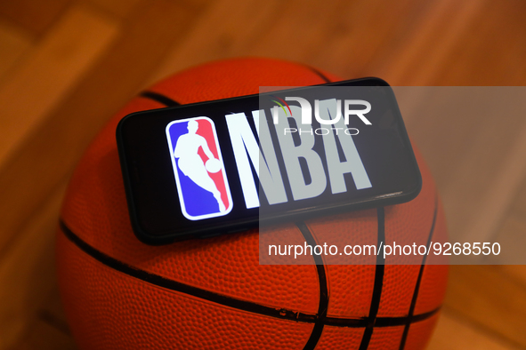 NBA logo displayed on a phone screen and a basketball are seen in this illustration photo taken in Krakow, Poland on December 1, 2022. 