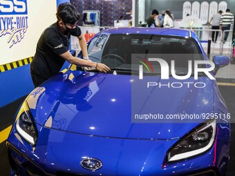A worker cleans the windshield of a car at the Urban Sneaker Society exhibition in Jakarta, Indonesia on December 9, 2022. The golden age of...