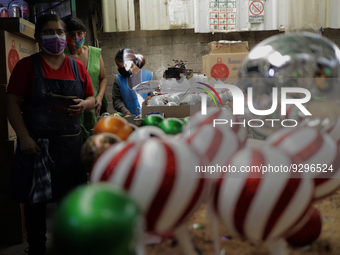 On the left, Josefina Aguilar, industrial biochemist and owner of a cooperative that produces handmade blown glass Christmas spheres in Tlah...
