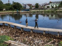 Men walks beside a river covered by garbage in Bogor, West Java, Indonesia, on Wednesday, December 17, 2022. The Earth is literally covered...