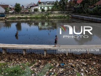 A boy walks beside a river covered by garbage in Bogor, West Java, Indonesia, on Wednesday, December 17, 2022. The Earth is literally covere...