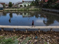 A boy walks beside a river covered by garbage in Bogor, West Java, Indonesia, on Wednesday, December 17, 2022. The Earth is literally covere...