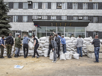 Men help to form a barricade as pro-Russian armed men in military fatigues stand guard outside a regional administration building seized in...