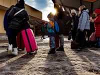 A toddler stands with his family as Ukrainians queue at the railway station in Przemysl, Poland  to depart for Ukraine on December 20, 2022....