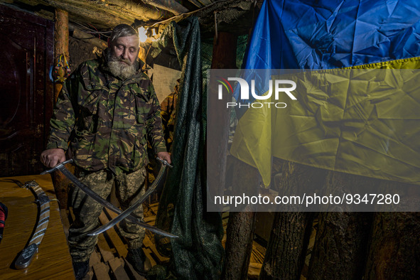 A soldier of a cossack battalion exhibits the ceremonial swords in the underground base of his unit near the frontlines of Zaporizhia region...