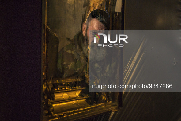 An orthodox icon reflects the face of an ukrainian soldier in his underground shelter while he waits during a russian shelling in Zaporizhia...