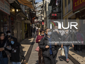People wearing face masks walking in a street at a popular tourist district on December 29, 2022 in Macau, China. (
