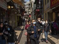 People wearing face masks walking in a street at a popular tourist district on December 29, 2022 in Macau, China. (