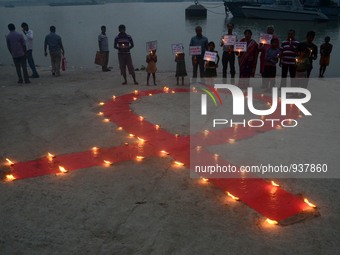 Indian volunteers and children lighting lamps on red ribbon to celebrate the  World AIDS Day on the banks of river Ganges in Kolkata , India...