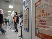People walks pass a sign for the Sinovac CoronaVac Inactivated Vaccine by China Biotechnology company, Sinovac Biotech Ltd. at a Covid-19 va...