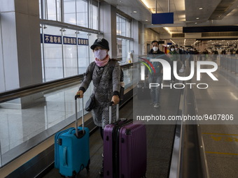 Travelers wearing face masks with suitcases crossing from Lok Ma Chau control point in Hong Kong to Futian Port in China on January 8, 2023...