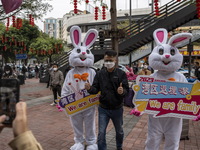A man posing for a photo with workers dress in rabbit suits welcome visitors outside Futian Port on January 8, 2023 in Shenzhen, China. Hong...