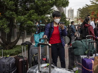 A women wearing a face mask with suitcases outside Futian Port on January 8, 2023 in Shenzhen, China. Hong Kong today resumes quarantine fre...
