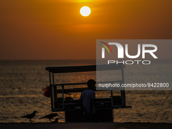 A vendor sells prawns, crabs, and rottie from his cart as the sun sets on the Galle Face promenade in Colombo, Sri Lanka, on January 11, 202...