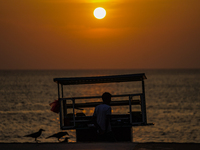 A vendor sells prawns, crabs, and rottie from his cart as the sun sets on the Galle Face promenade in Colombo, Sri Lanka, on January 11, 202...