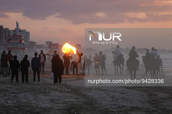A Palestinian youth show his skills with perform fire breathing on Gaza Beach during sunset, on January 12, 2023.    