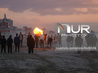 A Palestinian youth show his skills with perform fire breathing on Gaza Beach during sunset, on January 12, 2023.    (