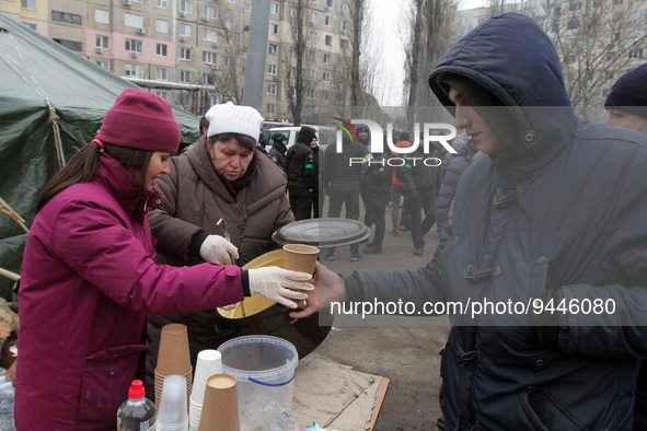 DNIPRO, UKRAINE - JANUARY 15, 2023 - People offer food and drinks outside an apartment block hit by a rocket launched by Russian occupiers d...