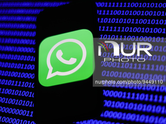 WhatsApp logo displayed on a phone screen and a binary code displayed on a screen are seen in this illustration photo taken in Krakow, Polan...