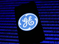 General Electric logo displayed on a phone screen and a binary code displayed on a screen are seen in this illustration photo taken in Krako...