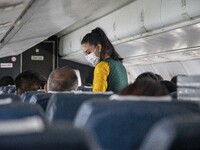 Flight attendant serving passengers during the flight. Inside the cabin of a Yeti Airlines ATR 72 propeller aircraft as seen on a flight fro...