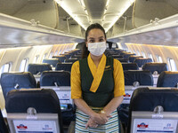 A flight attendant wearing a facemask inside the cabin of Yeti Airlines ATR 72-500. Flight attendant or air stewardess / air hostess is a me...
