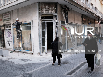 A priest is passing in front of a store that renovationing in Athens, Greece on January 18, 2023. (