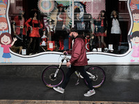 A man with his bicycle is passing in front of a store with carnival costumes in Athens, Greece on January 18, 2023. (