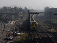 A suburban train is seen with a background of highrise buildings which are partially visible through dense smog in Mumbai, India, 18 January...