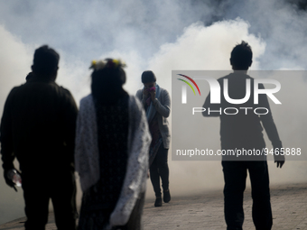 People walked past a garbage fire as it creates toxic smoke at a park area in Dhaka, Bangladesh on January 19, 2023. are burning beside a ro...